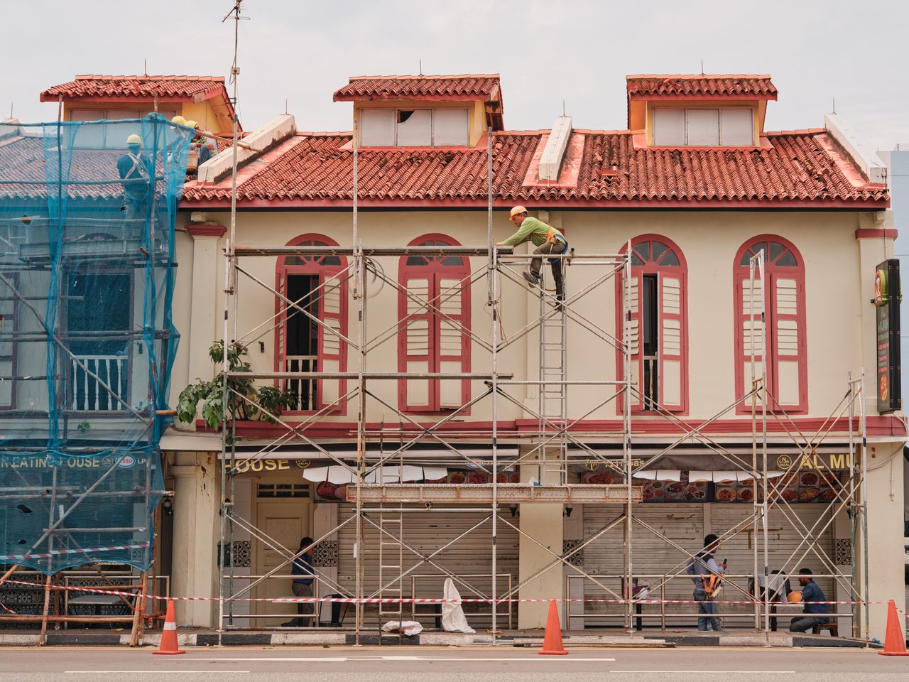 Home Workers on scaffolding renovating a historic building facade with red roof and tall windows.