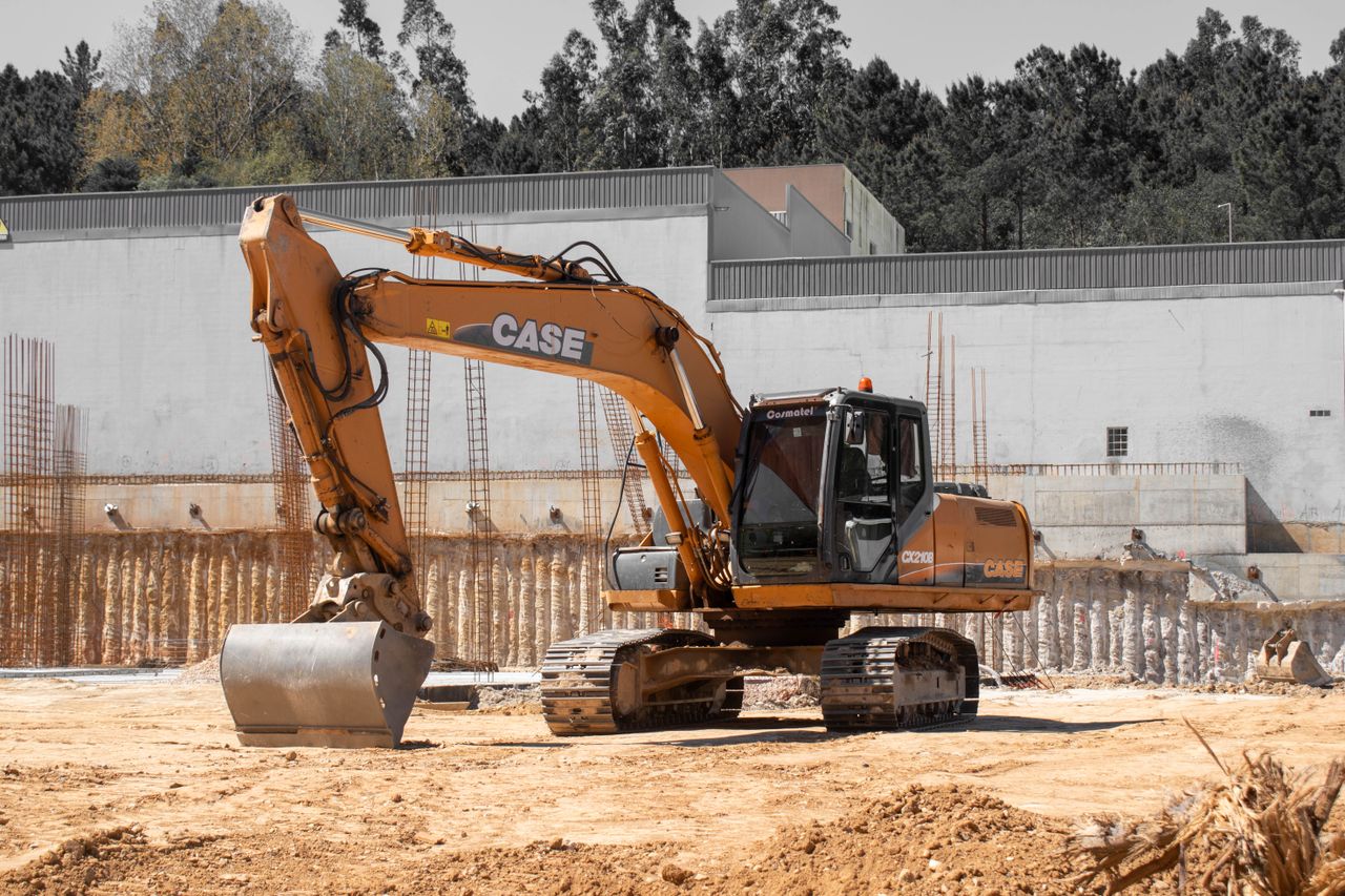 Home A large excavator positioned at an active construction site with clear skies.
