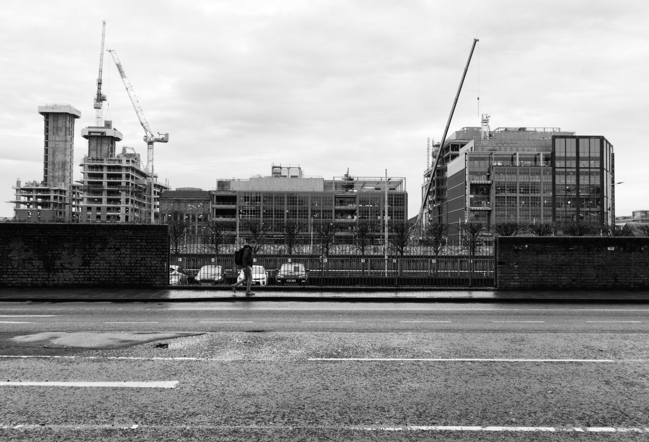 About Black and white photo of a construction site with cranes and buildings under development.